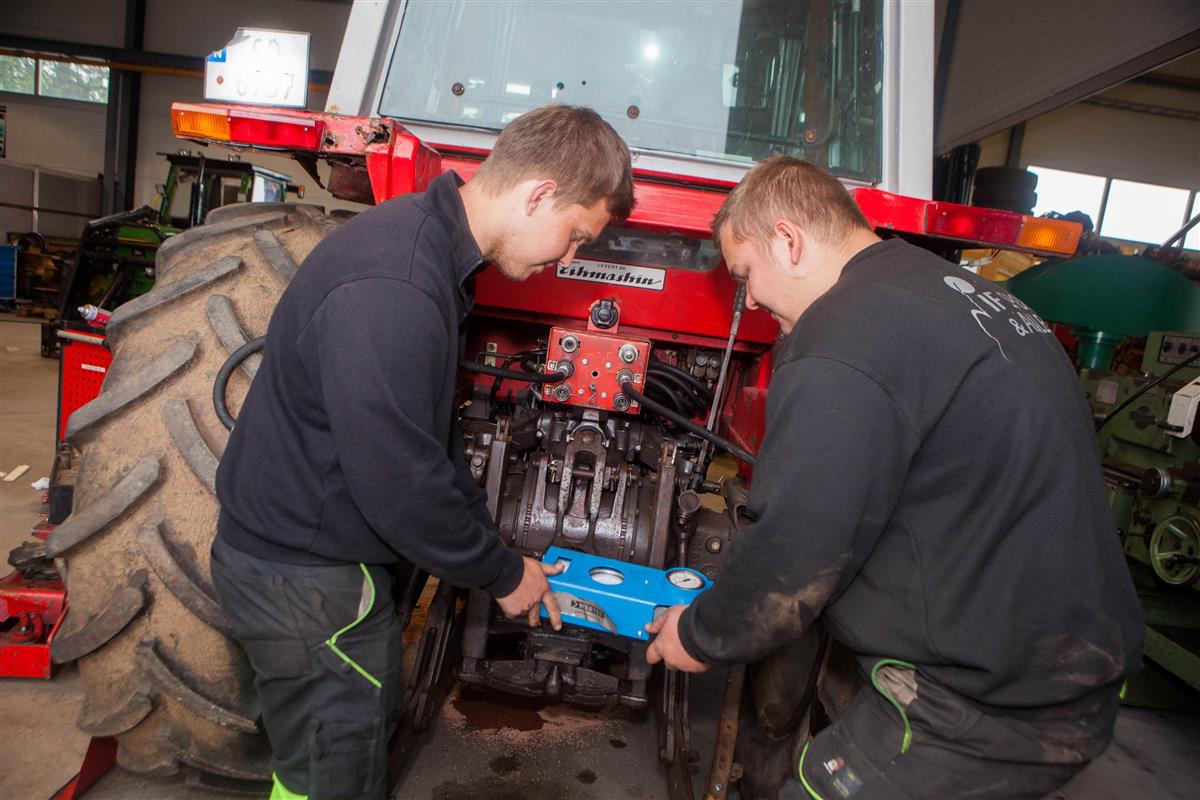 To elever reparerer en traktor. Foto. - Klikk for stort bilde